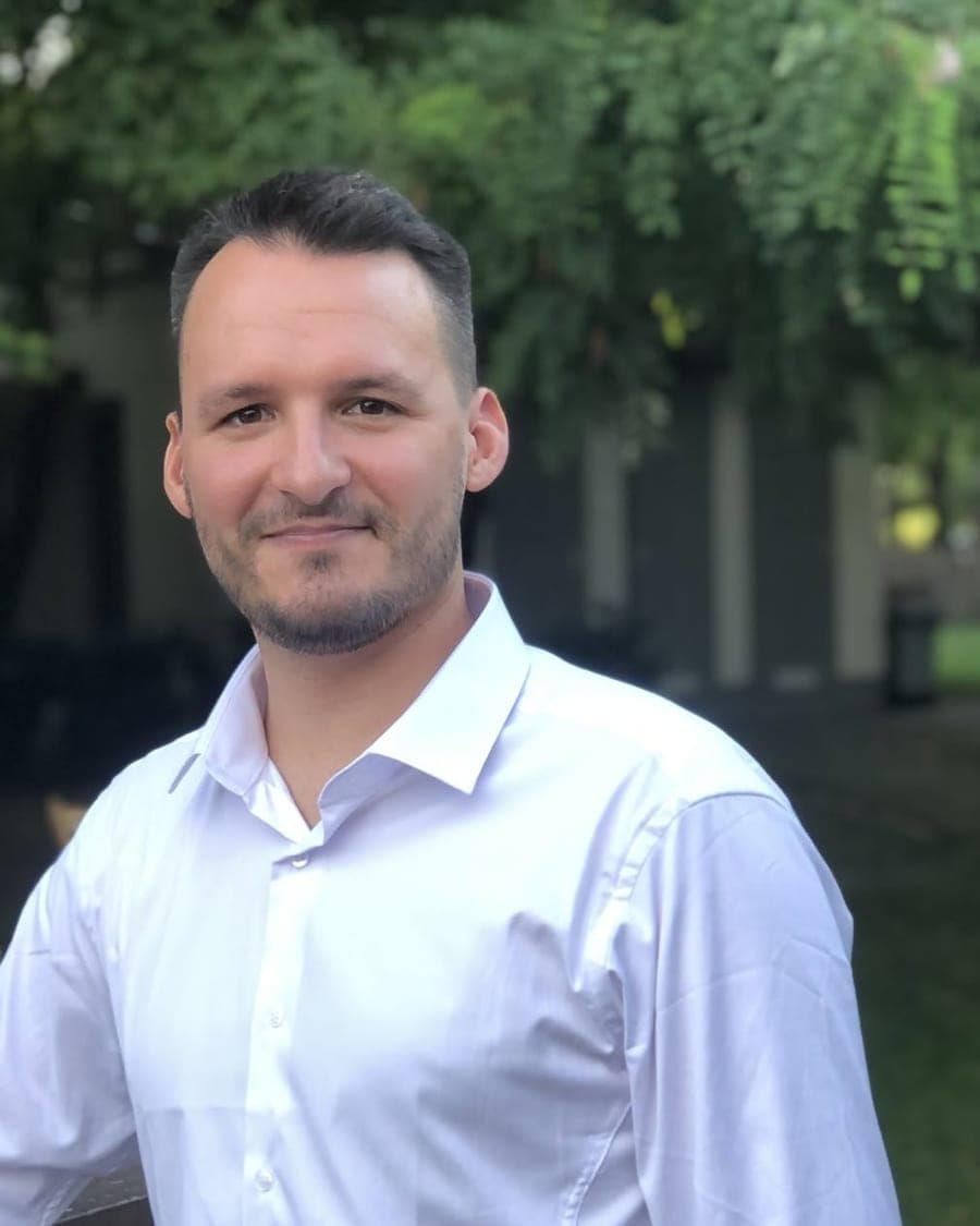 Bence Végh smiling, in a white shirt, outdoors